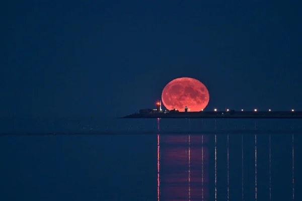 2021年8月23日 在爱尔兰都柏林Sandymount海滩上 罕见的夏季蓝龙月在爱尔兰杜恩 劳加尔灯塔之间的天空中升起 美丽的景色映入眼帘 巨大的月亮 — 图库照片