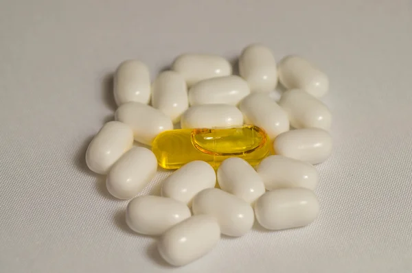 Yellow liquid filled bill between white pills — Stock Photo, Image