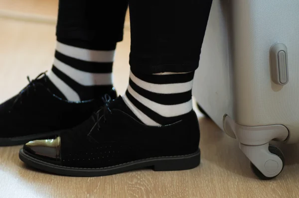 Zarif siyah deri ayakkabı ve siyah ve beyaz çizgili çorap ile bavul konseptiyle bekliyor — Stok fotoğraf