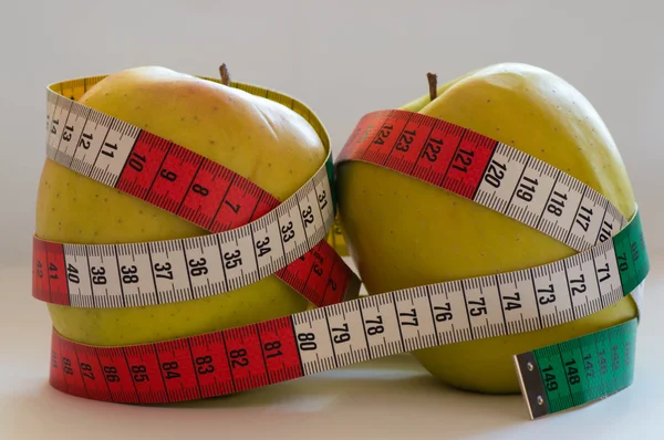 Two golden apples next to each other with measure tape around them — Stock Photo, Image