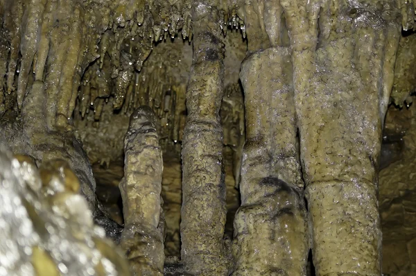 Stalagmiter och stalaktiter med vatten droppar på dem i en grotta — Stockfoto