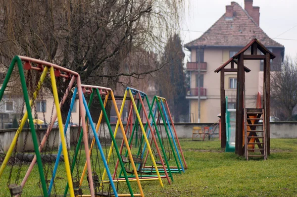 Parque infantil envelhecido com balanços e corrediça — Fotografia de Stock