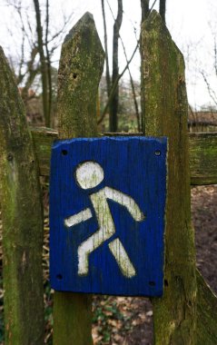 El yapımı dikdörtgen yol tabelaları. Tahtadan yapılmış. Mavi ve beyaza boyanmış. İşaret, yürüme yolunun başladığı çite vidalanmış..