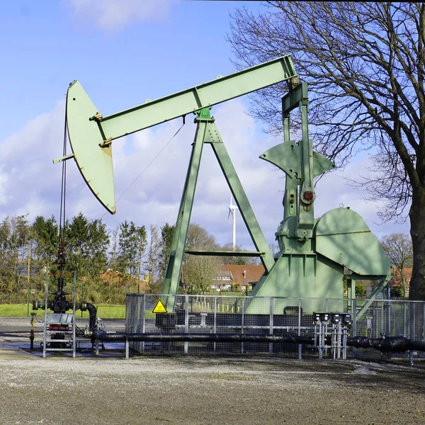 Oil drilling. Nodding donkey in use in Germany. It is used to pump oil out of the ground when there is not enough  pressure. Pump jack