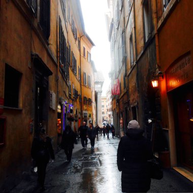 Roma, İtalya - 8 Mart 2016 - Yağmurlu bir günde Via del Seminario. Bu dar sokakta bir sürü insan var. Tarihi binaların duvarları sıcak Akdeniz sarısıdır..            