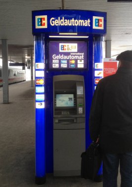 Hanover, Almanya - 12 Aralık 2012 Bir adam Hanover istasyonundaki uluslararası bir ATM 'ye bakıyor. Bu makine, normal banka kartlarına ek olarak, diğerlerinin yanı sıra kredi kartı kabul eder.