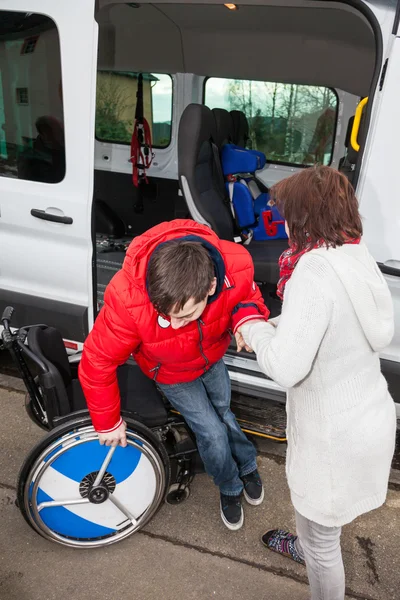 Matka pomaga syna niepełnosprawnych z autobusu szkolnego. — Zdjęcie stockowe