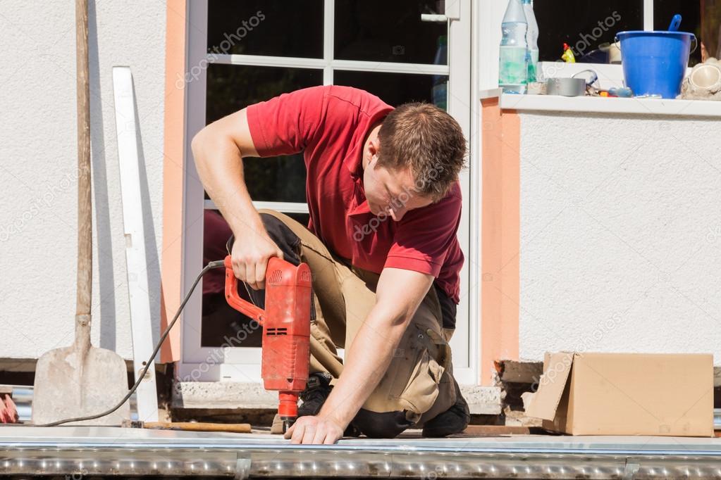 A young man drilling a hole with an impact drill