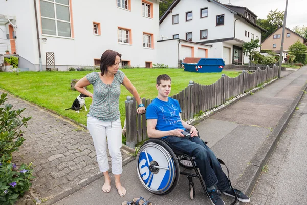 Mère avec fils handicapé attendant le bus scolaire — Photo