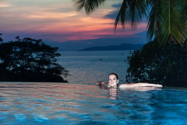 Uma mulher na beira de uma piscina com vista para o mar — Fotografia de Stock
