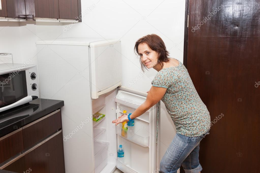 A woman shows with her hand in an empty fridge