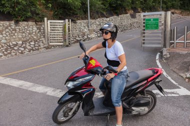 Kadın kask ve güneş gözlüğü ile bir scooter üzerinde