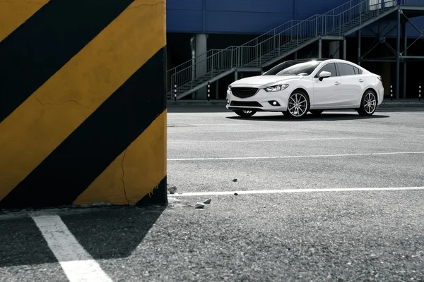 Белая машина остается на стоянке возле городского здания в дневное время — стоковое фото