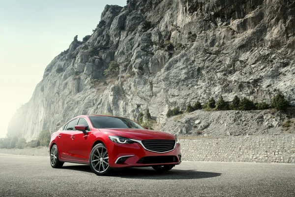 Red car standing on the road near mountains at daytime — Stock Photo, Image