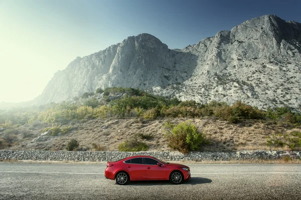 Röd bil stående på väg nära bergen på dagtid — Stockfoto