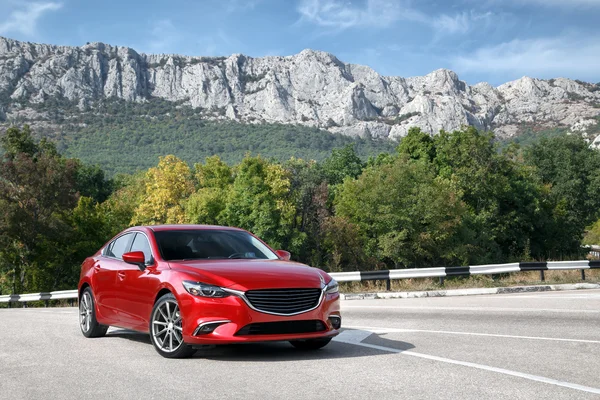 Kırmızı araba ayakta dağlar yakınındaki yolda gündüz