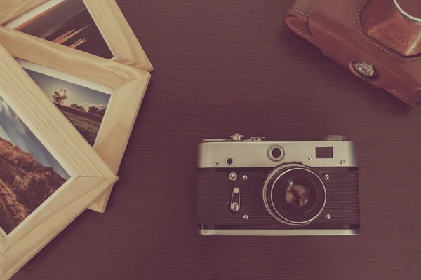 Retro vintage camera and photos in frame on wood background