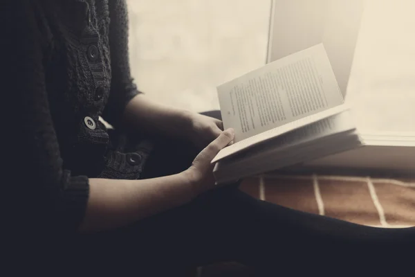 Жінка читає книжкове сидіння на дошці біля вікна — стокове фото