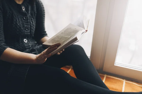 Жінка читає книжкове сидіння на дошці біля вікна — стокове фото