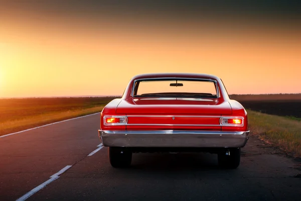 Coche rojo retro Chevrolet Malibu permanecer en la carretera de asfalto al atardecer —  Fotos de Stock