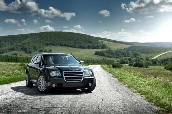 Coche negro Chrysler 300c de pie en la carretera de asfalto durante el día — Foto de Stock