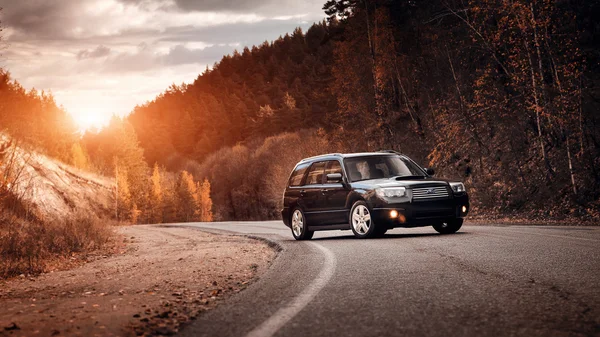 Черный автомобиль Subaru Forester стоит на асфальтированной дороге на закате — стоковое фото