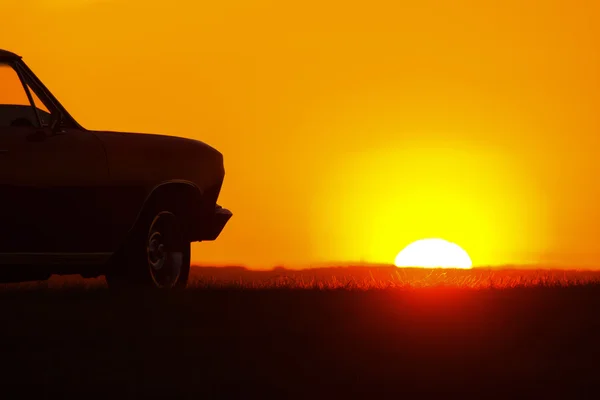 Retro rode auto op asfaltweg bij zonsondergang — Stockfoto