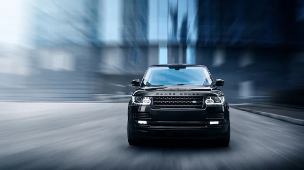 Coche Premium Land Rover Range Rover conduce rápido por carretera en la ciudad durante el día ; Fotos De Stock