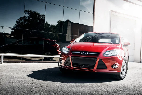 Red car Ford Focus III Sport standing near mirror build at daytime — Stock Photo, Image