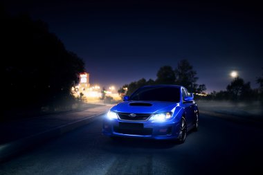 Mavi araba Subaru Impreza Wrx STI ay geceleri şehir ve orman yakın asfalt kırsal yolda kal