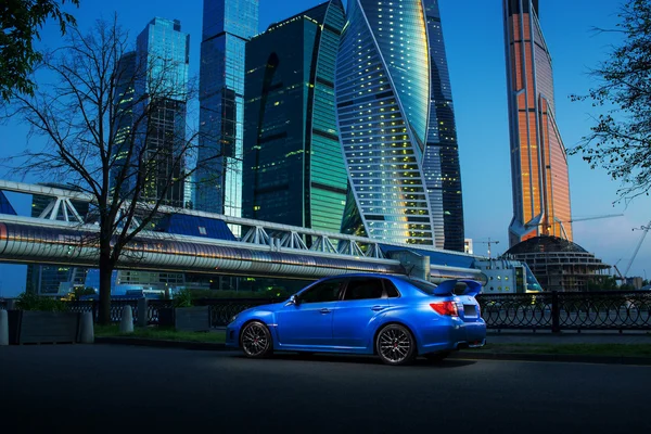 Голубой автомобиль Subaru Impreza WRX STI останавливается возле Международного бизнес-центра Москва-Сити в сумерках — стоковое фото