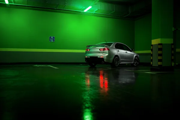 Gri araba Mitsubishi Lancer yeraltı park yerinde kal ve ıslak asfalt yansıtacak — Stok fotoğraf