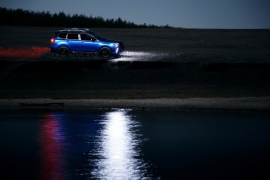 Araba Subaru Forester kırsal off-road standı ve gece su yansıyan