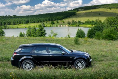 Siyah araba Chrysler 300c gündüz göl kenarında off-road standı