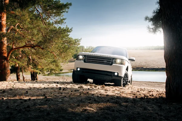 Car Land Rover Range Rover de pie en la arena cerca del lago y el bosque durante el día —  Fotos de Stock