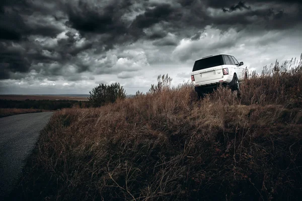Vit bil Land Rover Range Rover står på countyiside off-road vid dramatiska moln dagtid — Stockfoto