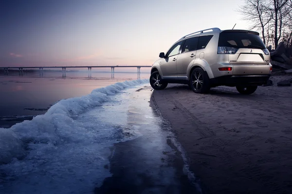 Bil Mitsubishi Outlander vistelse på isen kusten på vintern sunset — Stockfoto