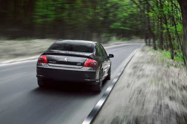 Peugeot 407 autem na krajinu lesní asfaltkou ve dne — Stock fotografie