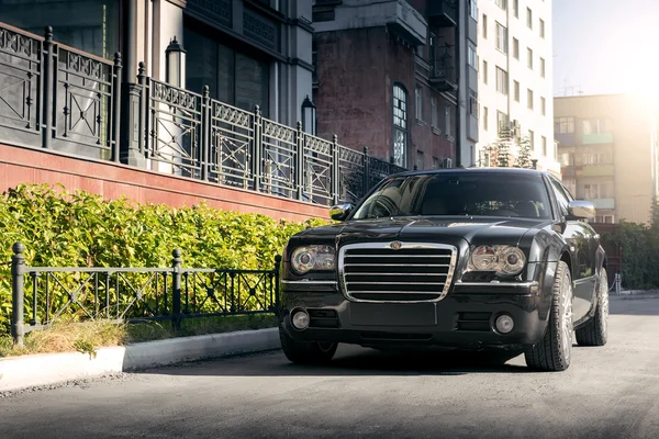 Voiture noire Chrysler 300c debout sur la route asphaltée dans la ville le jour — Photo