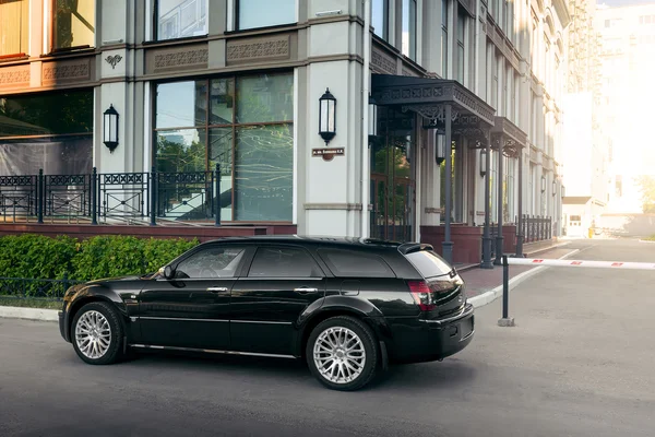 Svart bil Chrysler 300 c står på asfaltvei i byen på dagtid – stockfoto