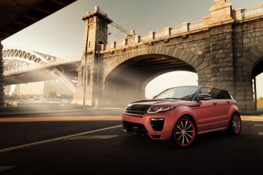 Gün batımında şehir Moskova'da asfalt yolda araba Land Rover Range Rover Evoque ayakta