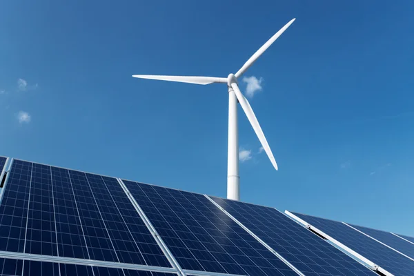 Molino de viento y paneles solares en el cielo azul durante el día — Foto de Stock