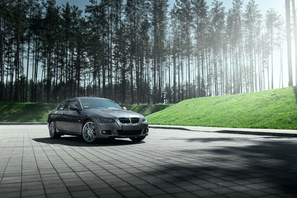 Coche BMW Coupe E92 de pie en el estacionamiento vacío sett cerca del bosque de pinos durante el día —  Fotos de Stock