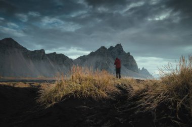 Tripodlu profesyonel manzara fotoğrafçısı doğa fotoğrafı çekiyor. İzlanda 'daki Stoksnes' de Vestrahorn Dağı