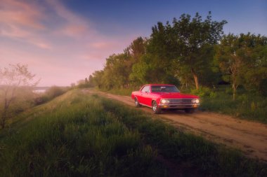 Engels, Rusya - 26 Mayıs 2021: Retro kırmızı kaslı araba Chevrolet Malibu Chevelle SS, Golden Sunset 'te kırsal yolda park halinde.