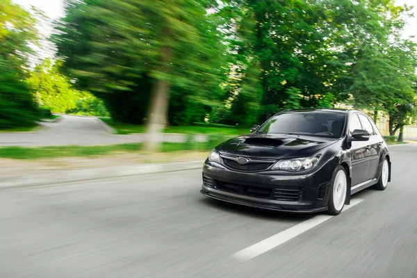 Vitesse de conduite de voiture rapide sur la route asphaltée arbres verts subaru impreza — Photo