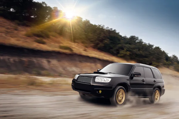 Car drive speed fast on the dust off-road subaru forester at sunset