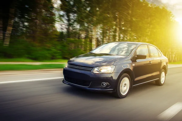 Быстрый привод скорости автомобиля на дороге в летнее время заката Volkswagen поло седан — стоковое фото