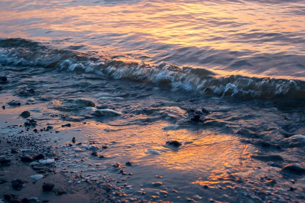 Vague venant sur la plage de sable au coucher du soleil — Photo