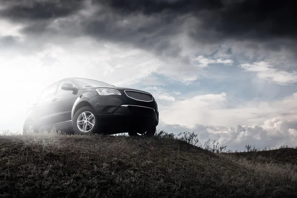 Zwarte auto Ssangyong Actyon verblijf op heuvel in dramatische wolken overdag — Stockfoto